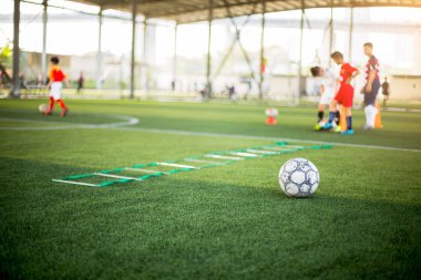 Yeşil yapay çimlerde bulanık futbol ve merdiven matkapları. 