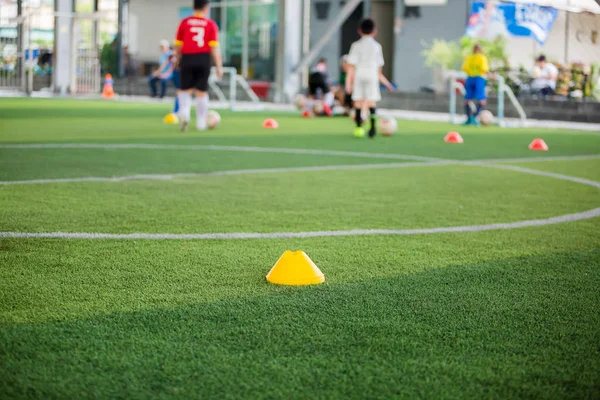 Marker Cone sul tappeto erboso artificiale verde con gioco di calcio bambino sfocato — Foto Stock