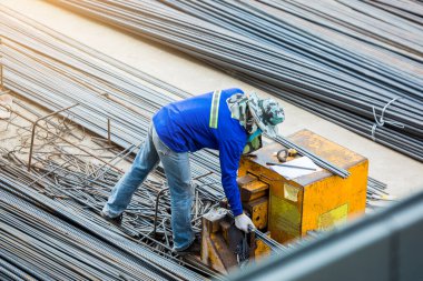 İnşaat işçisine ve inşaat alanında elektrikli demir kesme makinesiyle çalışan bir çok deforme çelik çubuğa seçici odaklanma. Büyük ölçekli yüksek ölçekli inşaat projesi.