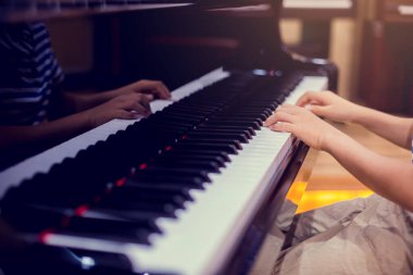 Piyano çalmak için çocuk parmaklarına ve piyano tuşuna özen göster. Konser için müzik aleti ya da öğrenme müziği var. Sahnede piyano çalan çocuk müzisyenin eli kapalı.