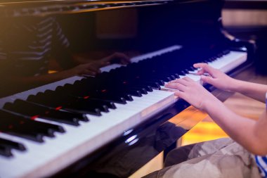 Piyano çalmak için çocuk parmaklarına ve piyano tuşuna özen göster. Konser için müzik aleti ya da öğrenme müziği var. Sahnede piyano çalan çocuk müzisyenin eli kapalı.