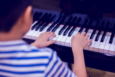 Piyano çalmak için çocuk parmaklarına ve piyano tuşuna özen göster. Konser için müzik aleti ya da öğrenme müziği var. Sahnede piyano çalan çocuk müzisyenin eli kapalı.