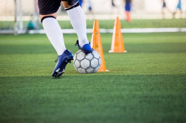 Futbolcu futbol antrenmanı için koni işaretleri etrafında koşuyor ve topu kontrol ediyor. futbol akademisi.