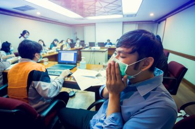 Toplantı odasında maske takıp öksüren bir işadamı. Coronavirus Covid-19 enfeksiyonu olan Asyalı bir erkek hasta. Coronavirus Covid-19 'un yayılması kavramı.