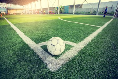 bulanık oyuncu arka plan ile futbol alanının köşesinde yeşil suni çim üzerinde futbol topu, bulanık çocuk futbolcuları ile köşe tekme için köşede futbol, futbol eğitimi veya futbol maçı.