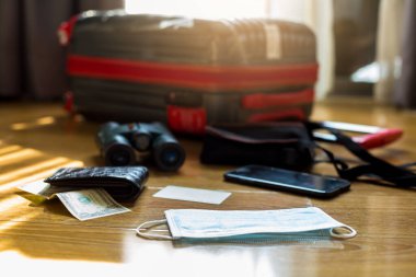 Bulanık bavulu olan ilaç maskesi, para, kredi kartı, dürbün ve seyahat ekipmanı. Coronavirus gibi enfeksiyonların yayılmasını önlediğine inanılan bulanık el dezenfektanı ile cerrahi maskeler.