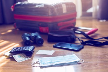 Bulanık bavulu olan ilaç maskesi, para, kredi kartı, dürbün ve seyahat ekipmanı. Coronavirus gibi enfeksiyonların yayılmasını önlediğine inanılan bulanık el dezenfektanı ile cerrahi maskeler.