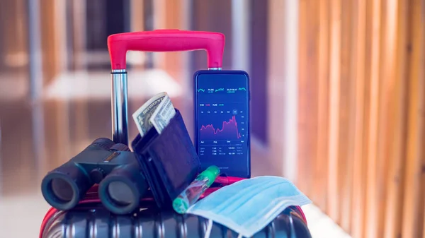 医療用マスク ドル札 双眼鏡やホテル内の荷物の上の旅行機器とスマートフォン上の赤いグラフ 経済の概念はコヴィト19世からのものである 旅行業の低迷 — ストック写真