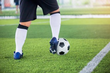 Futbolcu topu yeşil suni sahada atmak için topu kontrol ediyor. Erkek futbolcu maç için antrenman yapıyor. Futbol akademisinde futbolcu..