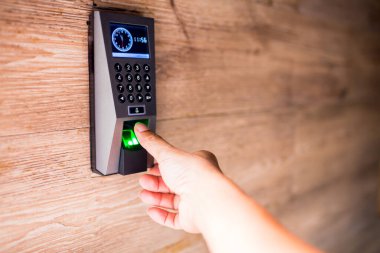 Adam kapıya ulaşmak için elektronik kontrol makinesine parmağını bastır. Personel, ahşap duvardaki kapıyı açmak için parmak taramasıyla elektronik kontrol makinesini aşağı itecek..