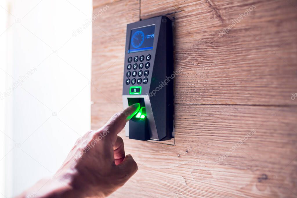 man push finger down on the electronic control machine to access the door. Staff push down electronic control machine with finger scan to open the door at wooden wall.