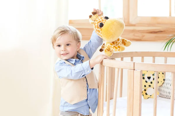 Boy Stands Next Cot Nursery Holds Toy His Hands Kid — Stock Photo, Image