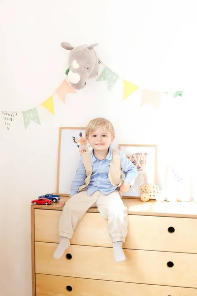 Een Jongetje Zit Een Dressoir Naast Een Witte Muur Met — Stockfoto