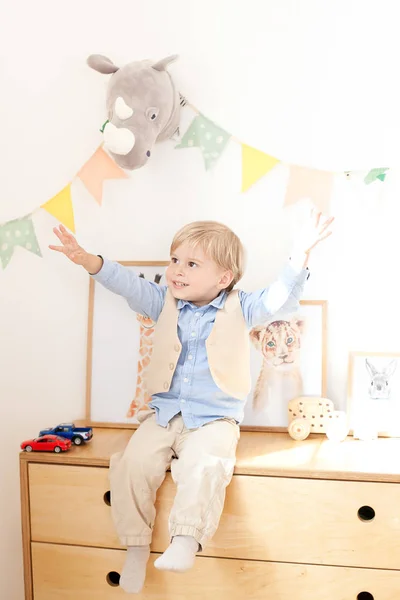 Маленький Хлопчик Сидить Комоді Біля Білої Стіни Прапорами Іграшками Портрет — стокове фото