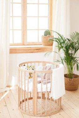 Çevre dostu rahat bir iç mekanda ahşap bir beşik. Açık kahverengi çocuk odası ve ahşap boş bir beşik. Konforlu ev Hygge Stili Tasarım. İskandinav tarzında çocuk odası. Kırsal iç mekan