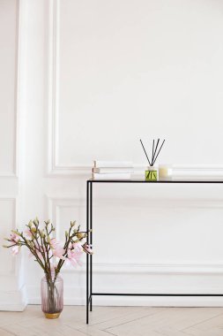 Reed ayırıcı oturma odasındaki masanın üzerinde. Yatak odasındaki şifoniyerin üzerinde mum olan el yapımı kamış spreyi. İskandinav ev dekoru: mum, aroma yayıcı, bir buket manolya ile vazo. 