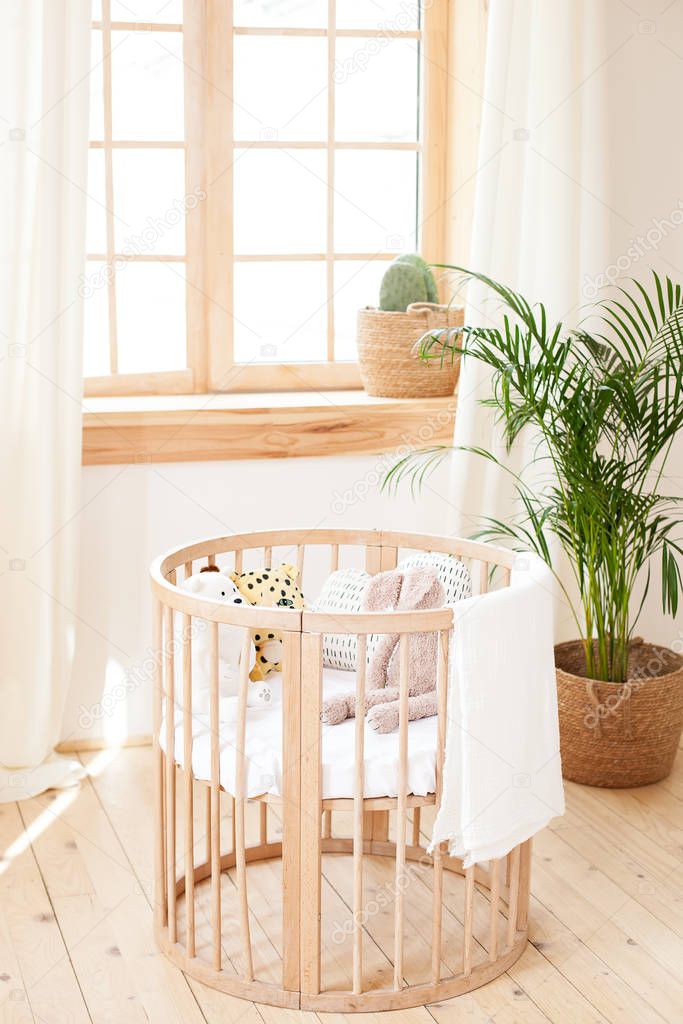 Wooden crib in an environmentally friendly cozy interior. Light brown children bedroom with a wooden empty crib. Cozy house Hygge Style Design. Children room in the Scandinavian style. Rustic interior