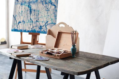 Sanatçının atölyesi. Ahşap masadaki sanat aletleri. Eğitim konsepti. Sanatçı atölyesinde, suluboya atölyesinde, fırçalarda, palette, sehpada ve resim aletlerinde karmaşa. Tasarımcının işyeri, hipster tarzı..