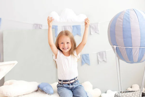 カジュアルな服の少女は 装飾的な風船の背景に雲の枕を保持しています 子供は子供部屋で遊ぶ 子供の頃の概念 誕生日や祝日の飾り — ストック写真