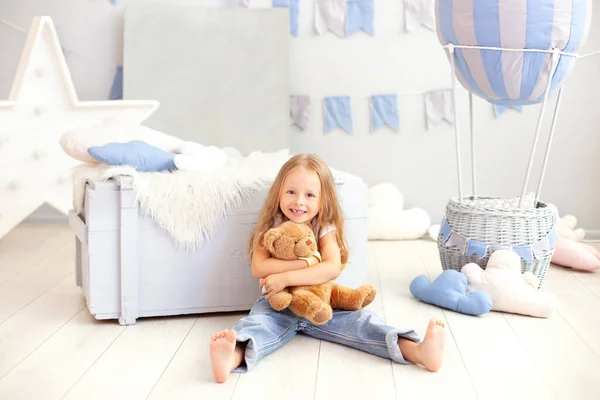 小さな金髪の女の子の笑顔は 装飾的な風船の背景にテディベアを抱きます 子供はおもちゃで子供部屋で遊ぶ 子供の頃 旅行の概念 誕生日や祝日の飾り — ストック写真
