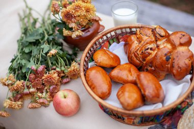 Eski köy masasında açık hava pikniği. Ekmek, çörek, elma ve çiçek buketi ile sonbahar parkında ahşap masa üzerinde güzel bir kırsal piknik kompozisyonu. Sağlıklı gıda konsepti. Kimse yok.