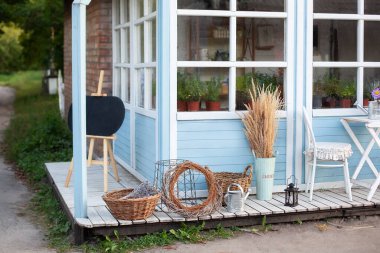 Bahçe aletlerinin yanında hasır sepetler, sulama tenekesi ve kurutulmuş çiviler, mavi bir evin duvarında pampa otları. Bahçe işleri konsepti. Hasat. Kır evinin rahat dekorasyonu. Kırsal biçim. 