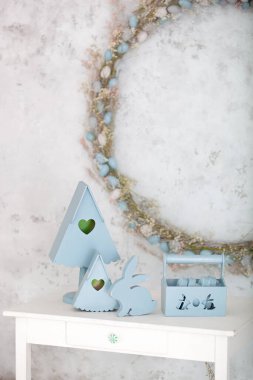 Mavili ev dekorasyonu ahşap bir sepet dekoratif yuva kutuları ve şirin bir tavşandır. Paskalya süsleri. Yazlık köy kompozisyonu, beyaz bir masanın üzerinde ahşap bir yuva kutusu var. bahar odası dekoru