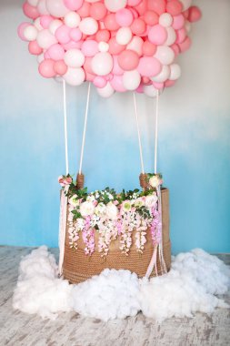 Çiçeklerle süslenmiş sepetli balonlardan Aerostat. Arka planda hava uçuşu için balon sepeti. Bulutlu mavi gökyüzü. Çocuk partisi, doğum günü için bayram dekoru. Düğün Dekorasyonu