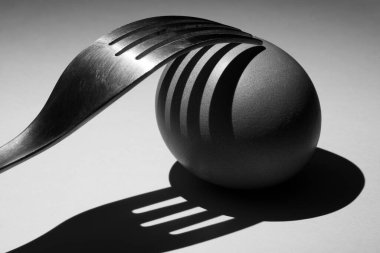 Çatal, yumurta ve gölgeleri, beyaz arka planda yakın plan.