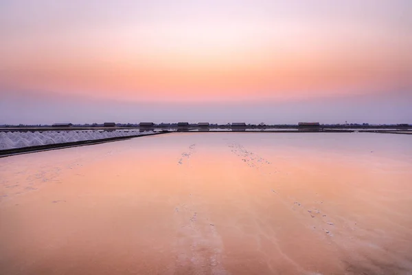 Beautiful landscape salt farm sunset refection on the water and salt crystal at Samutsakhon Thailand