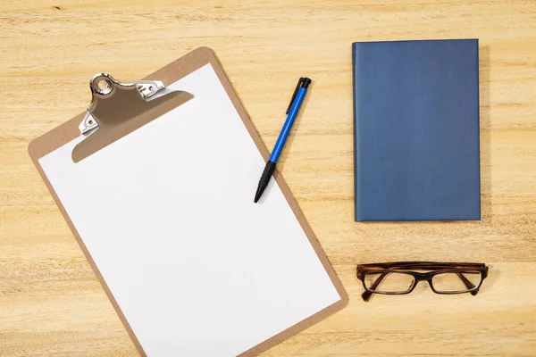 Platt ligg, övre vyn kontorsbord skrivbord. Arbetsplats med blank clip board, penna, glas och dagbok på träbord. Förlöjliga, kopiera utrymme — Stockfoto