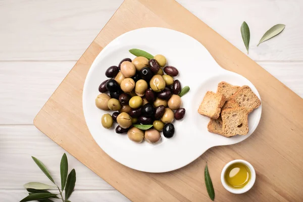 Marinated olives in plate on wooden table. Tasty mediterranean food.