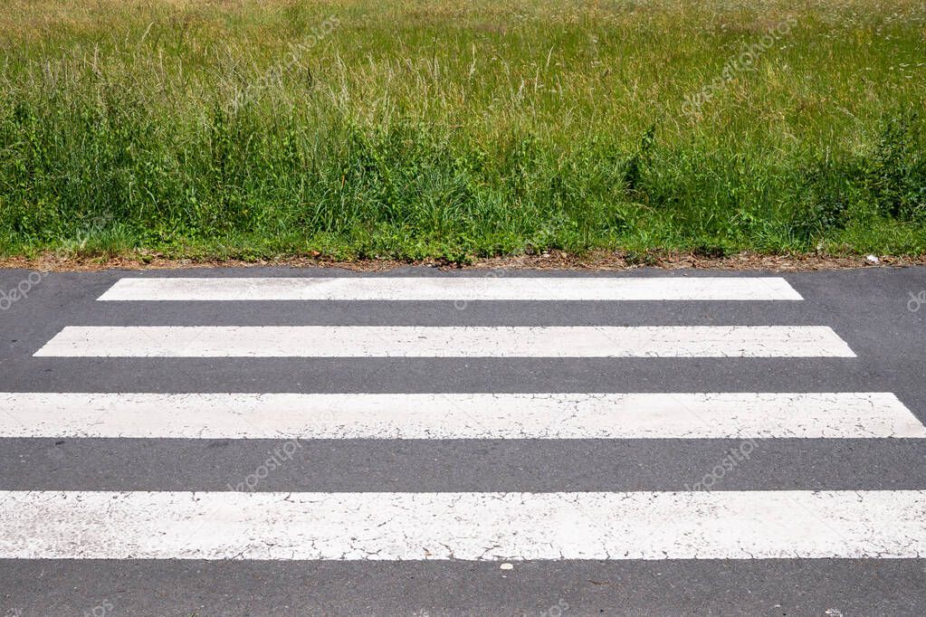 Crosswalk that ends on meadow. Urbanization concept