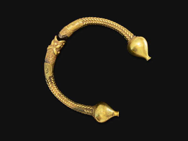 Antique golden bracelet called torc isolated on black background