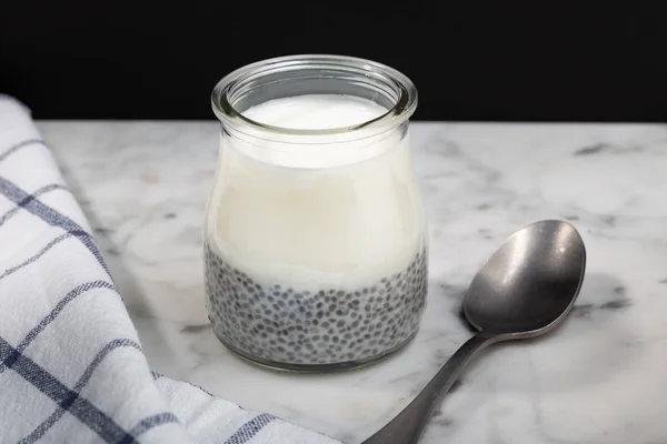 Greek yogurt chia pudding with raisins in glass on marble table