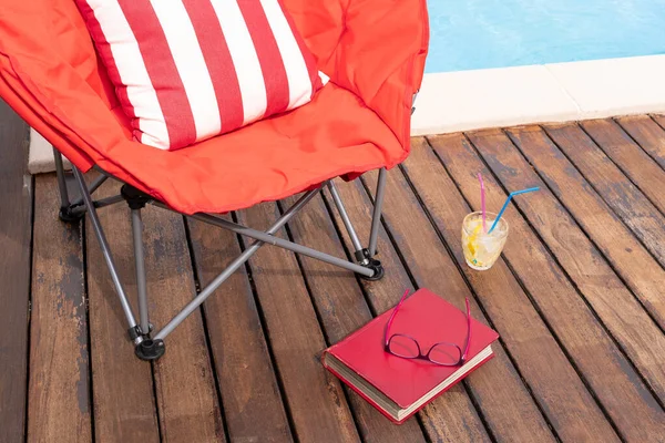 Escena de verano con piscina, silla, bebida y libro —  Fotos de Stock
