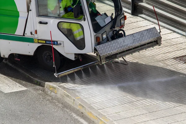 Street cleaning machine working in city. Sweeper cleaning the sidewalk with pressurized water. Maintenance or cleaning concept