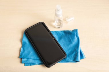 Cep telefonu, bez ve alkol spreyi şişesi masada. Temiz akıllı telefon kavramı