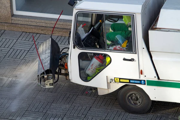 Street cleaning machine working on a sidewalk. Sweeper cleaning the sidewalk with pressurized water. Maintenance or cleaning concept