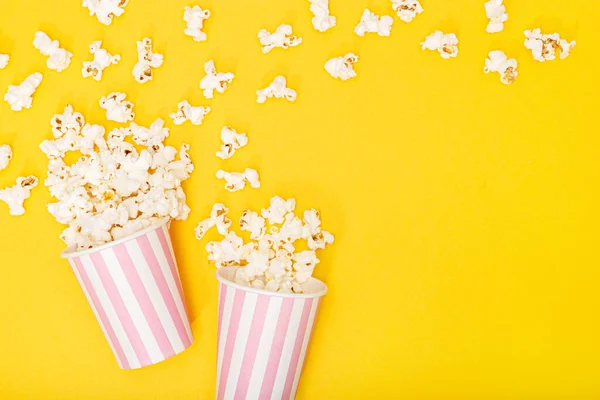 Popcorn bucket on yellow background. Movie or TV background. Top view Copy space