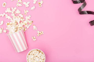 Patlamış mısır kovası ve pembe arka planda film şeridi. Film ya da televizyon geçmişi. Üst Görünüm Kopyalama alanı