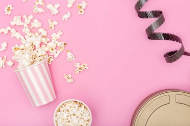 Patlamış mısır kovası, film şeridi ve pembe arka planda film kutusu. Film ya da televizyon geçmişi. Üst Görünüm Kopyalama alanı