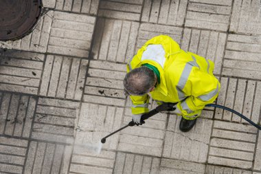 Worker cleaning the sidewalk with pressurized water. Maintenance or cleaning concept. Top view clipart