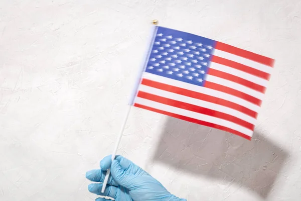 Mão Proteção Luva Segurando Bandeira Americana Contra Fundo Texturizado Branco — Fotografia de Stock
