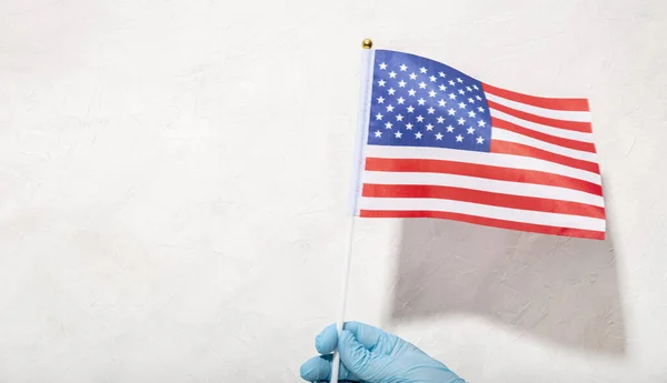 Mão Proteção Luva Segurando Bandeira Americana Contra Fundo Texturizado Branco — Fotografia de Stock