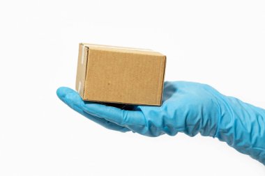 Teslimatçı, plastik eldivenlerin içinde karton kutu tutuyor. Coronavirus COVID-19 salgını sırasında online alışveriş ve paket teslimatı