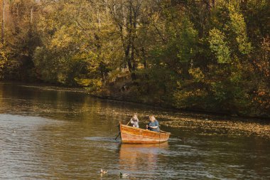 Aile gölde yelken açıyor. Sıcak renkli ağaçları ve gölü olan güzel bir manzara..