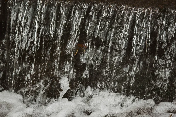 Cascada de piedras en el parque. Sobre el fondo del follaje otoñal y árboles de color naranja y amarillo . — Foto de Stock