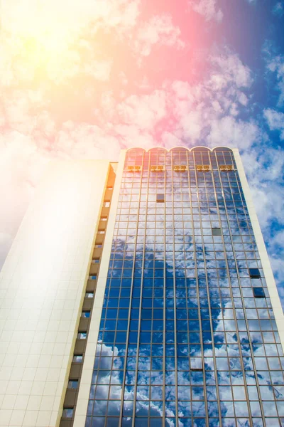 Un rascacielos con muchas ventanas contra un hermoso cielo azul. Concepto empresarial y financiero . — Foto de Stock