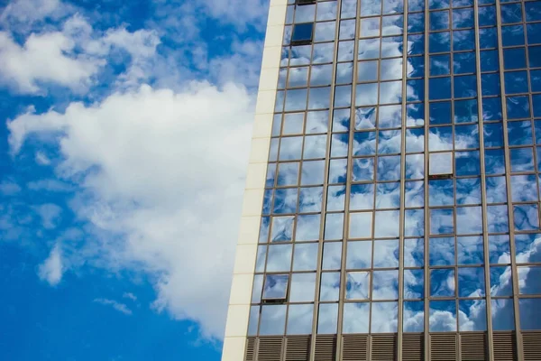 Un rascacielos con muchas ventanas contra un hermoso cielo azul. Concepto empresarial y financiero . — Foto de Stock